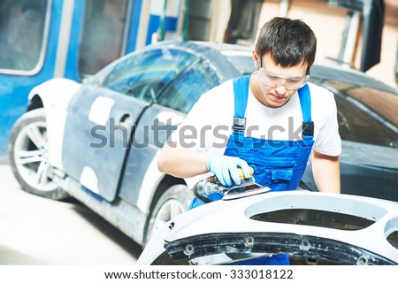 auto mechanic worker  polishing bumper car at automobile repair and renew service station shop by power buffer machine