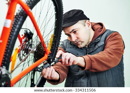 Bike maintenance. mechanic serviceman repairman installing assembling or adjusting bicycle gear on wheel in workshop