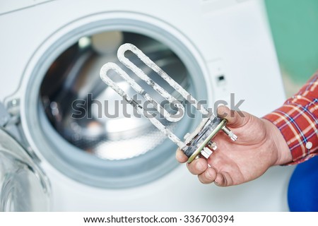 Washing machine repair. Hand of repairer with turbular electric heating element