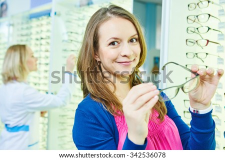young woman choosing eye glasses in optician store