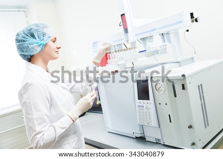 Pharmacy and chemistry theme. Female scientific researcher putting flask with liquid solution in gas chromatography