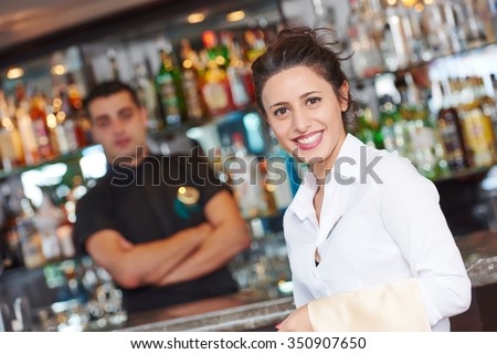 waitress restaurant catering service. Female cheerful restaurant worker with barman at background