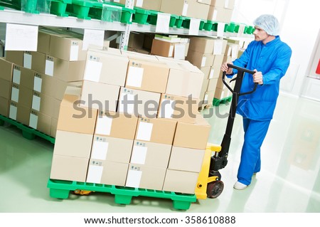 medical warehouse worker man loading boxes with medcine drugs by hand forklift at pharmacy factory