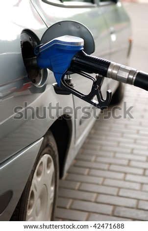 fuelling nozzle inserted into petrol tank at gas station for gasoline filling