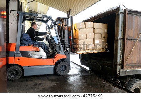 Electric forklift in warehouse loading cardboard boxes