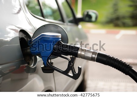 fuelling nozzle inserted into petrol tank at gas station for gasoline filling