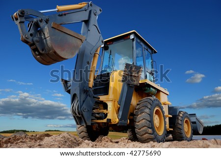 Excavator Loader with raised backhoe standing over cloudscape sky