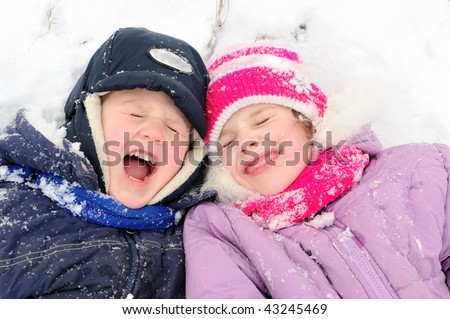 little happy girl and boy laughing at snowy winter outdoors