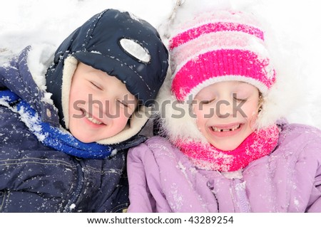 little happy girl and boy laughing at snowy winter outdoors