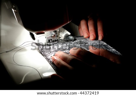 two woman hands sewing on the stitching machine