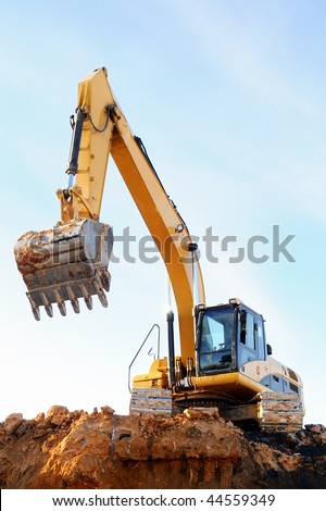 stock photo : Yellow excavator loader at construction site with raised bucket over blue sky