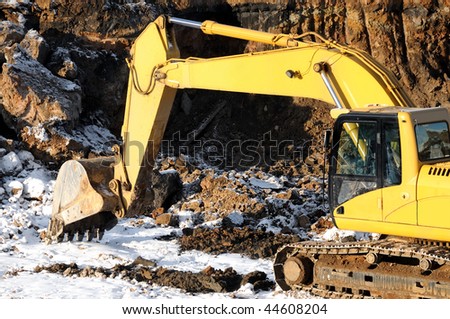 Yellow excavator loader at construction site with raised bucket in open cast