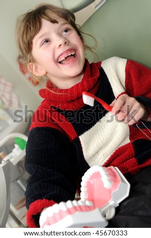 happy smiley little girl and medical training of tooth cleaning at dentist