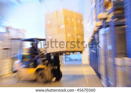 Electric forklift in warehouse loading cardboard boxes. Intentional optical zooming blur