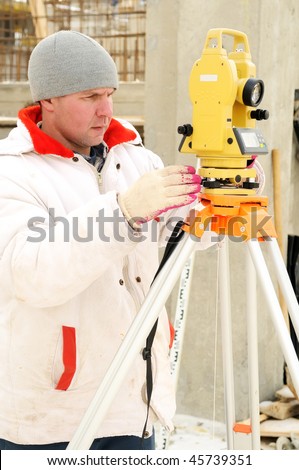 Land surveyor and equipment theodolite at a construction site in winter