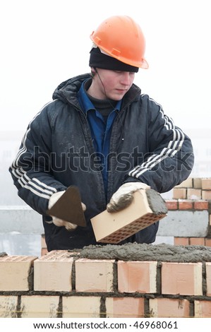 A brick layer worker building a brick wall at construction site