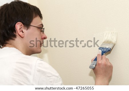 Painter worker at decoration work painting a wall with brush