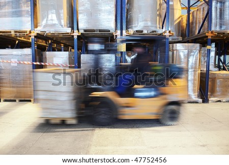 worker driving a forklift loader in warehouse with load on the pallet