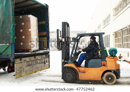 warehouse forklift loader loading cardboard boxes into a car outdoors