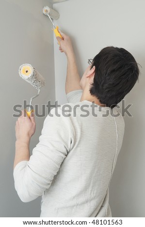 Painter worker at decoration work painting a wall with brush