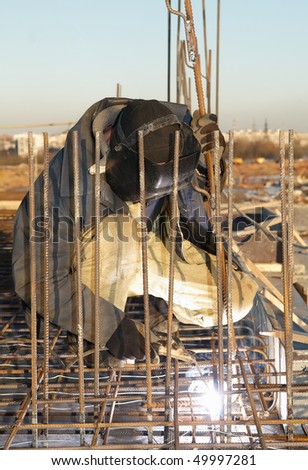 worker welding by electrode a metal lattice reinforcement for concrete pouring
