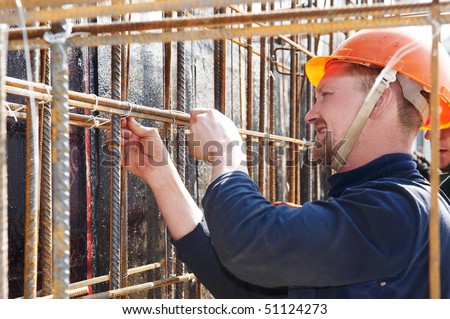 worker in helmet making metal mash at construction site for concrete pouring