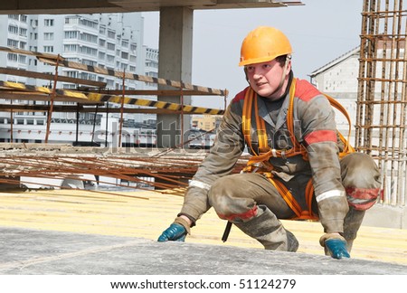 Young builder worker in work wear, helmet and equipment at house building area