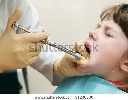 Dentist making anesthetic injection to child gum before milk tooth extracting