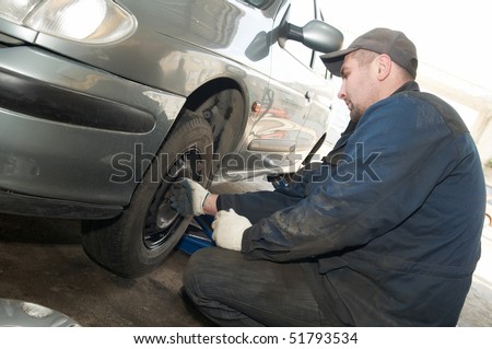 repairman making tyre fitting with air compressed wrench (screwing up bolts)