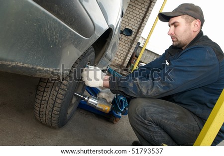 repairman making tyre fitting with air compressed wrench (screwing up bolts)