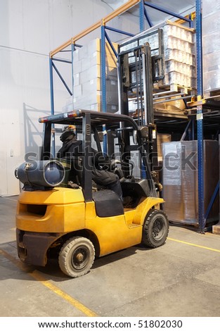 worker moving up the load with a forklift loader in warehouse