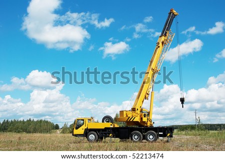 yellow automobile crane with rise n telescopic boom outdoors over blue sky