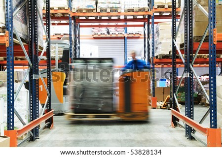 low level picker loader with driver moving in a warehouse