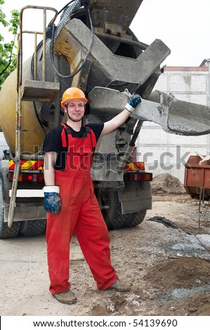 Happy worker builder controlling concrete mixer filling process at construction site