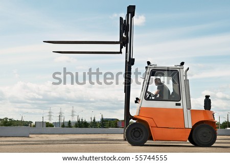 Forklift loader for warehouse works outdoors with risen forks
