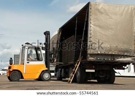 Forklift loader for warehouse works outdoors loading (unloading) a long lorry truck