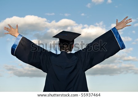 graduate student in cloak with open arms over blue sky (rear view)