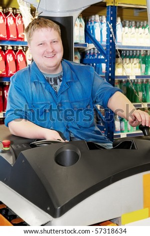 young smiley warehouse worker man driving forklift stacker loader truck in product depot