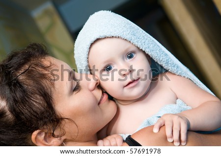 Mother and baby child after shower. Baby covered in bath towel