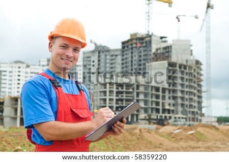 One happy builder worker with clipboard inspecting works at construction site