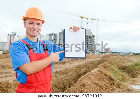 One smiley builder worker pointing the finger to clipboard over construction site