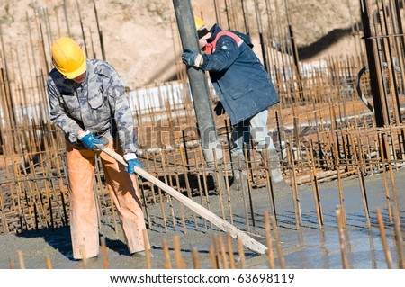 two builder workers during concrete works at construction site. Leveling and pouring