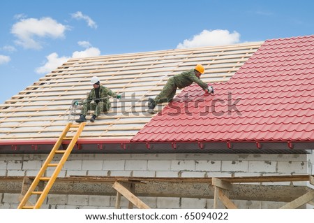 two workers on roof at works with metal tile and roofing iron