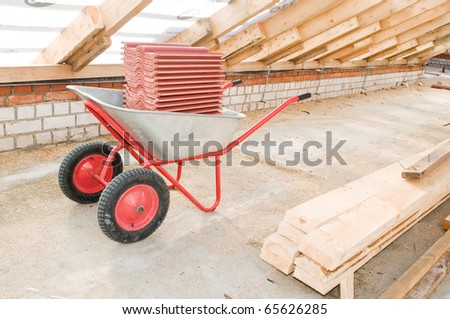 professional galvanized wheelbarrow loaded with reg clay tile at roofing works area