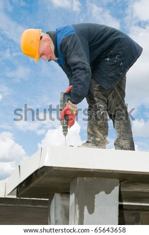 construction worker builder drilling a hole during roofing iron mounting at plate roof works