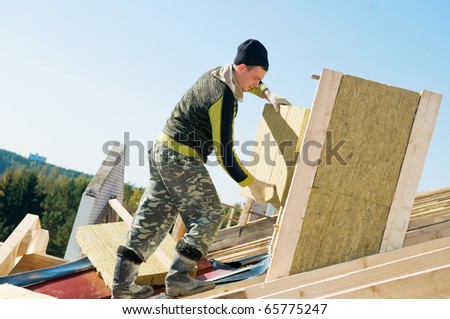 builder roofer working with insulation material at construction works
