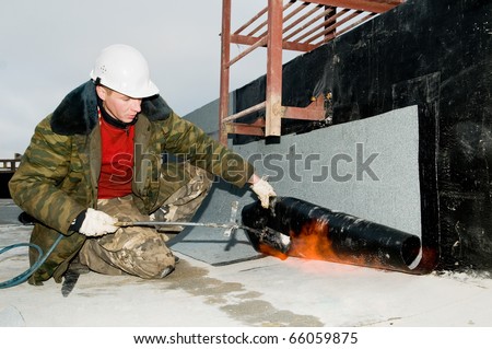 Roofing asphalt bitumen felt installation with heating and melting roll by torch on flame