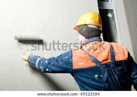 facade worker at decoration plastering works outside building wall with roller