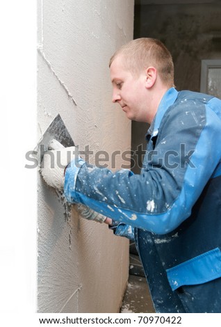 Plasterer at indoor renovation decoration with putty knife
