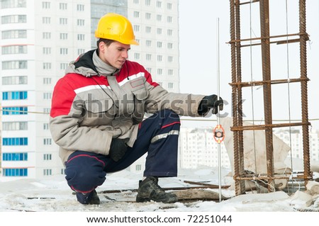 Surveyor worker assistant working at construction site in winter with survey target
